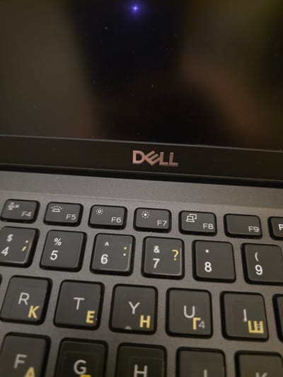 The image displays a close-up view of a Dell laptop keyboard and the screen bezel. The Dell logo is visible in silver on the black bezel above the keyboard. The keyboard is black with gray and yellow lettering. Several keys are clearly visible, including function keys F4 through F9, along with number keys 4, 5, 6, 7, 8, and 9. The letter keys R, K, T, E, Y, H, U, and Г4 are also visible, as are the symbols $, %, ^, &, *, (, and ). The image does not provide any information about the city of Brzeg, Poland, or any people, actions, or interactions. The environment appears to be indoors, with the laptop resting on a surface that is not visible.