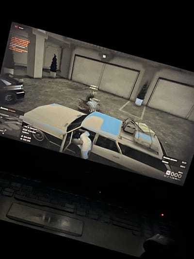 The image depicts a scene from a video game, likely a simulation or role-playing game, viewed from a slightly tilted angle. The primary subjects are a light-colored vehicle with a blue roof section, parked in what appears to be a dimly lit garage or industrial area with large, corrugated doors. Two figures are present: one is bent over near the open driver's side of the vehicle, possibly interacting with its contents or mechanics, while another figure, dressed in lighter clothing, is partially visible inside the vehicle, leaning towards the driver's side.

The vehicle has items strapped to its roof, suggesting it is either packed for a journey or has been involved in some activity. The ground is a rough, concrete-like surface. In the background, there are large, gray, roll-up doors, typical of a garage or warehouse. To the left of the vehicle, there is a white rectangular object on the ground. Further to the left and slightly below the vehicle, there appears to be a dark, jagged opening in the floor or a structure, possibly a hole or a damaged area.

Visible text elements from the game's user interface are present in the upper right and lower sections of the image. The text includes "Суббота" (Saturday), a timestamp "17:47 04.04.2008", financial figures "$24 649" and "$39 250", and other game-related labels like "Осталось преме" (Remaining time), "Marpaan", "ACAGS", and "000円". The overall ambiance is dark and somewhat utilitarian, consistent with an indoor or nighttime setting within a game environment. There are no clear indications of weather conditions. The activity appears to be focused on the vehicle and the figures' interaction with it.