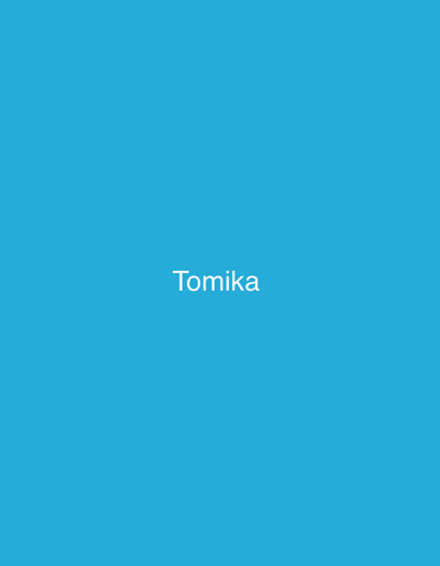 The image is a simple, solid blue background with the word "Tomika" written in white, sans-serif font in the center. There are no other discernible objects, people, or environmental details present. The location of Safari, Nigeria, is not visually represented in this image.