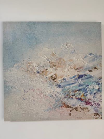 The image shows a close-up, top-down view of an abstract painting. The painting features a textured surface with thick applications of paint, creating a dimensional effect. The colors are primarily cool tones, with dominant shades of white, light blue, and hints of purple, red, and gold. The left side of the painting is a soft gradient of light blue. The right side is dominated by thick white impasto strokes, with textured patches of gold leaf and small flecks of color. The overall impression is one of movement and energy, possibly evoking natural elements like clouds, water, or ice formations. There is no visible text, people, or specific objects that would indicate a particular scene or event. The setting appears to be indoors, with the painting displayed against a plain white background, likely a wall. There are no cues about the time of day, weather, or specific location beyond the provided context of Kizilyurt, Russia, which is not visually discernible from the image itself. The artwork evokes a sense of calm and beauty, with the textures adding a tactile quality to the visual experience.