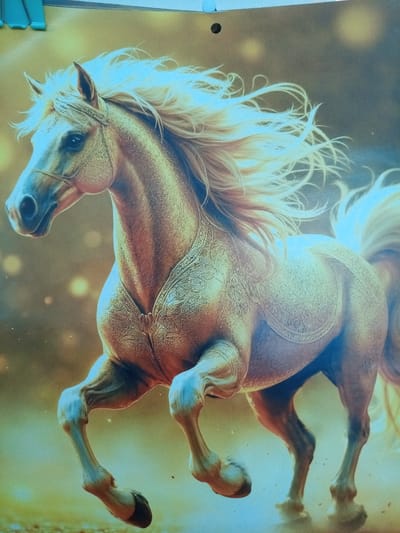 The image displays a digital painting of a golden horse in motion. The horse has a flowing white mane and tail, and is adorned with an ornate, light-colored saddle blanket featuring intricate patterns. The background is a gradient of warm, hazy yellow and brown tones, with blurred circular lights suggesting a mystical or ethereal atmosphere. The horse's musculature and the texture of its coat are rendered with a high level of detail. There are no people or any identifiable urban or natural elements suggesting a location in Yurga, Russia, or any specific geographical setting. The image appears to be a standalone artwork without any context linking it to a particular place or event.