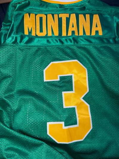 The image displays the back of a green jersey with yellow lettering. The word "MONTANA" is prominently displayed across the upper back. Below the name, a large yellow number "3" with a white outline is centered on the jersey. The fabric of the jersey is a mesh material. There is no indication of the city of Nikopol, Bulgaria in this image.