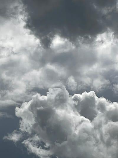 This is a close-up, full-frame shot of a cloudy sky. The clouds are a mix of dark gray and white, with fluffy, billowing shapes. There are no visible landmarks, people, or objects in the image, and therefore no information about the city of Petrushenko, Russia can be inferred.