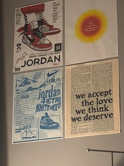 The image shows four square prints arranged on a light grey surface.

Top left: A print with a yellow and orange circular gradient, and the text "555 CHANGE something new is coming" in a small font inside the circle.
Top right: A print designed as a newspaper page filled with illegible text in a small font, with the phrase "we accept the love we think we deserve" in bold, vertically stacked black text.
Bottom left: A print depicting a red and white Air Jordan sneaker in a cartoon style, with text that includes "Kim Special collector's issues JORDAN I CHICAGO X OFF-WHITE", "JORDAN", "ISSUE 32", and a list of names.
Bottom right: A print featuring a design related to Nike and Air Jordan, including a sneaker image, a Nike swoosh logo, the word "JORDAN" in different fonts, the text "jordan 4 RETRD WHITE OREO", and a section with Japanese text.

No information about the location in the city of Whitby, Canada is included.
