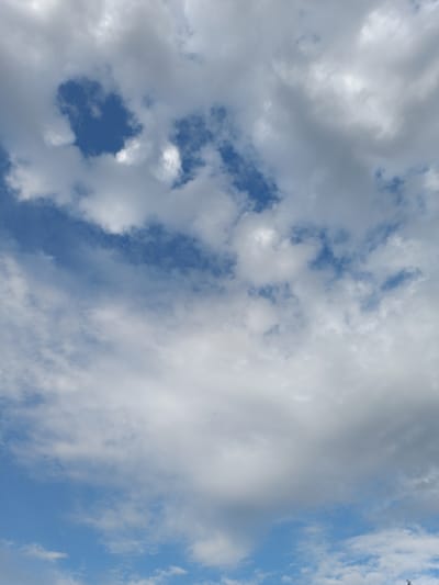 The image displays a cloudy sky with patches of blue visible through the clouds. The clouds are varied in appearance, with some being bright white and fluffy, while others are darker and more ominous. The scene is a wide shot of the sky, with no identifiable landmarks or structures, and thus cannot be pinpointed to any specific location in Leușeni, Moldova, or any other city. There are no people, subjects, objects, or actions depicted in the image. The environment is solely the sky.