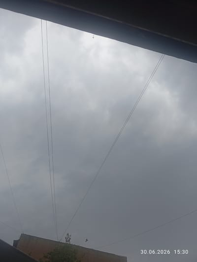 The image shows a cloudy sky with several power lines stretching across it. In the lower left corner, the roofline of a building is visible, and a bird is in flight in the lower right quadrant. The timestamp on the image indicates it was taken on June 30, 2026, at 15:30. The location is specified as Ohangaron, Uzbekistan.