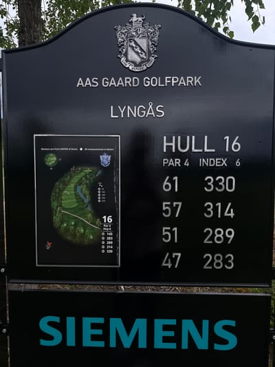 The image shows a sign for the 16th hole at the Aas Gaard Golfpark in Lyngås, likely located in Hakadal, Norway. The sign is primarily black with white text and a black frame. It displays the name of the golf park, the hole number, the par and index information, distances to the hole in meters, and a course map of the hole. The name "SIEMENS" is displayed on an adjacent sign. The image is taken outdoors with trees visible in the background.