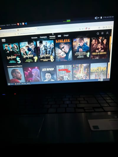 The image shows a laptop screen displaying the HBO Max website, featuring a selection of movies and series. The website is in Bulgarian, indicated by the titles such as "Хари Потър" (Harry Potter), "Фантастични Животни" (Fantastic Beasts), and "Улица на кошмарите" (Nightmare Alley). The upper right corner of the screen shows the date and time as "17:02, Jun 28, Sun", suggesting it is Sunday, June 28th, at 5:02 PM. The location of Dalgopol, Bulgaria, is not visible in the image and cannot be inferred from the provided visual information. The scene appears to be indoors, likely in a home or personal space, with the keyboard of the laptop visible in the foreground, partially illuminated by the screen's glow. There are no people visible in the scene, only the content displayed on the screen.