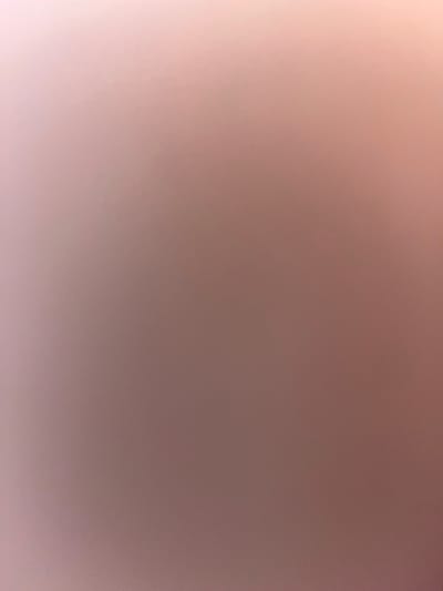 The image displays an abstract color gradient, devoid of any discernible subjects, objects, or a specific scene. It transitions smoothly from a bright, pale pink or creamy white hue in the bottom-left and left side, gradually darkening into a muted brownish-mauve or plum shade towards the top-right and right side. The overall appearance is soft and blurred, with no distinct textures or sharp features. There is no activity or event taking place within the frame. The brighter area suggests a light source originating from the lower-left, casting a gentle illumination that fades across the image. No specific time of day, weather, or location cues are visible, nor are there any emotions or visible text. The image is purely a study in color transition.