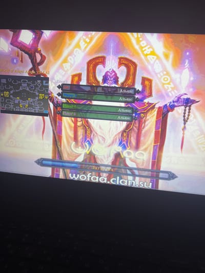 This image appears to be a screenshot of a computer game, likely an "Age of Wonders" or similar real-time strategy game given the interface elements. The primary subject is a fantasy scene with a large, ethereal figure in the background, possibly a deity or powerful being, rendered with bright, glowing colors. In the foreground, there is a game interface displaying player information, including names like "Player 2," "Player 7," and "Player 8," and clan affiliations in Russian, such as "Альянс" (Alliance) and "Клан 1" (Clan 1). There's also a minimap in the bottom left corner of the screen. The text "World of Angel Arena v17.4 AI" suggests the game title and version. Another piece of text, "wofed.clan.su," is visible on the right, likely a website address related to the game community. The overall scene is vibrant and fantastical, with an emphasis on magic and combat elements. The time of day and weather are irrelevant as it's a digital representation. The location context of Nikopol, Ukraine, is external to the image content itself. The emotions conveyed are likely those of engagement and strategy associated with playing a game.