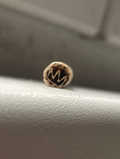The media file is a close-up, macro photograph of the end of a rolled cigarette or similar item. The object is positioned vertically, with its end facing the camera. The interior of the roll shows a spiraled pattern of what appears to be organic material, possibly tobacco or cannabis. The outer paper wrapping is light brown.
To the right of the cigarette, a textured, off-white surface is visible. This surface has a consistent, pebble-like texture, suggesting it could be part of an upholstered seat, a piece of furniture, or a similar material with a raised pattern. The lighting in the image is soft, highlighting the textures of both the cigarette's interior and the textured surface.
To the left of the cigarette is a blurred background, appearing as soft grey and brown tones, indicating a shallow depth of field. This blur suggests the focus is exclusively on the cigarette and its immediate surroundings. There are no people visible, nor is any text discernible within the image. The overall impression is one of focused detail on a small, everyday object in an indoor setting. The provided location context of Teplice, Czechia, does not offer specific visual cues within the image itself.