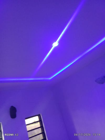 The image displays a ceiling with ambient blue lighting. Two distinct illuminated lines, one brighter than the other, run diagonally across the ceiling. In the lower left portion of the image, the text "REDMI A3" is visible, suggesting the device used to capture the photograph. The lower right corner shows a timestamp: "06/17/2026 15:14". A window with horizontal bars is visible on the left wall. A dark, irregular object is affixed to the wall near the window. The overall scene is dimly lit with a prevalent purple hue cast by the lighting. There is no indication of the location being in Nawfia, Nigeria.