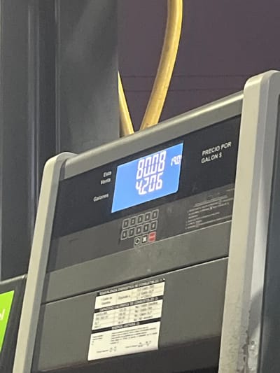 The image shows a close-up of a gas pump display. The display indicates a price of 19.0, a total of 00.08, and 4.206 gallons dispensed. The display unit is gray. The text above the price reads "PRECIO POR GALON $". The image contains a segment of a yellow hose. The pump appears to be located at a gas station in Lurín, Peru.