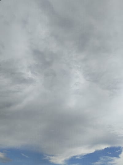 The image depicts a sky filled with clouds. The upper portion of the image is dominated by dense, gray clouds, suggesting overcast conditions. Towards the bottom, patches of blue sky are visible, interspersed with lighter, wispy clouds. The scene is a natural outdoor environment with no discernible structures or people. The specific location in Bulaev, Kazakhstan, cannot be determined from the visual information provided.