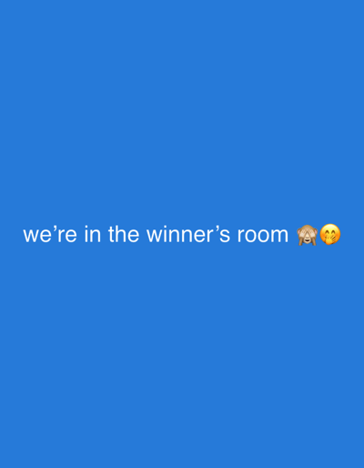 The image is a plain blue background with white text that reads "we're in the winner's room" followed by two emojis: a monkey covering its eyes and a face with open eyes and a smiling mouth. There are no discernible features that would allow for identification of a location in Ascot, United Kingdom. The image appears to be a digital graphic or a screenshot, not a photograph of a physical scene.