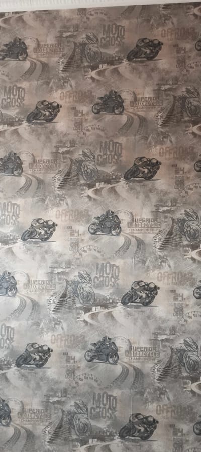 The image is a close-up, vertical shot of a wallpaper with a distressed, monochrome motorcycle racing theme. The wallpaper features numerous graphics of motorcycles, some appearing to be in motion on tracks or off-road terrain. Interspersed with the motorcycle imagery are text elements, including "MOTO CROSS," "OFFROAD," "SUPERIOR MOTORCYCLE CHAMPIONSHIP," and numbers like "24," and speed indicators resembling a speedometer with values up to 140. The overall aesthetic is gritty and energetic, with a sepia-toned or faded black and white appearance. There are no visible people, animals, or specific architectural landmarks that would indicate a location in Aktanyshbash, Russia; it is a decorative wallpaper pattern.