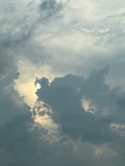The image is a photograph of a cloudy sky, taken from a low angle looking upwards. The clouds are a mix of dark, stormy gray and lighter, wispy white. In the center of the frame, a bright patch of sunlight breaks through the clouds, creating a dramatic contrast. The light is warm and golden, suggesting either sunrise or sunset. The overall mood of the image is one of awe and perhaps a touch of foreboding, due to the presence of the darker storm clouds. There is no visible text in the image. The location context of Brashlen, Bulgaria, provides a geographical anchor, but there are no specific visual cues in the photograph to pinpoint this exact location. The image captures a moment of dynamic weather, with the interplay of light and shadow across the sky.