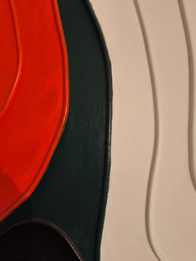 This is a close-up, abstract image of a textured artwork with distinct curved shapes and colors. A prominent area of vibrant orange is bordered by a dark green section. To the right of the dark green, there are flowing, wave-like forms in a light, creamy color. The textures appear to be raised or embossed.

There is no information in the image that would allow for the determination of its location in the city of Bolshaya Martynovka, Russia, or any other specific location. The image is an abstract close-up and does not contain any elements that are indicative of a particular place, such as landmarks, signage, or identifiable environmental features.