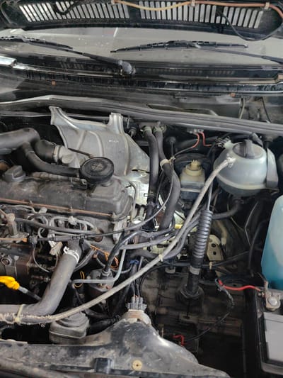 The image depicts the engine compartment of a vehicle. The engine is visible, along with various components such as hoses, wires, reservoirs, and other mechanical parts. The image contains a wiper blade assembly along the top. It is unlikely to be identifiable to a specific location in Slatina, Bulgaria, without additional information or context clues.