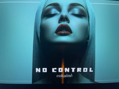 This is a cover image featuring a close-up of a woman's face. She has her eyes closed and is wearing bold, glossy red lipstick. Her head is draped in a hood or veil, creating a sense of mystery. Below her face, the words "NO CONTROL" are prominently displayed in large, white, block letters. Beneath this, the word "cokainé" is written in smaller, stylized lettering. The overall aesthetic is dark and dramatic, with a striking contrast between the woman's features and the text against a muted, greenish-blue background. There are no discernible location cues, time of day, or weather information. The emotion conveyed is ambiguous, perhaps one of intense focus, surrender, or artificiality. The image is likely related to music or a similar form of media.