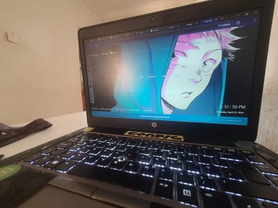 An eye-level shot captures a black HP laptop open on a white surface, revealing a brightly lit screen and a backlit keyboard. The laptop's screen displays a Google Chrome browser window with multiple tabs open, including "trello.com", "23RPDO", and "AI Mode." The main content of the new tab page is an anime-style wallpaper featuring a character with spiky pink hair and striking eyes, identified by text as "Jujutsu Kaisen Anime Wallpaper HD New Tab." Below the wallpaper, the time "1:51:50 PM" and date "Thursday, April 23, 2026" are visible. Chrome's New Tab page elements like "Most Visited," "Apps," "Share," and quick links such as "youtube," "google docs," and "chatgpt" are also displayed. Options like "Settings," "Change Wallpaper," and "Customize Chrome" are at the bottom of the screen.
The laptop's keyboard features glowing white backlighting, illuminating the QWERTY layout. A yellow sticker with the text "Eonsfg" is affixed above the keyboard, near the HP logo. To the left of the laptop, a dark, reddish object, possibly a strap or tool, rests on the white surface. The background consists of a light-colored, possibly off-white, wall, with a small, L-shaped white object attached to it in the upper left corner. The scene depicts a computer in active use, likely in an indoor setting within Oke Ogun, Nigeria, during the early afternoon.
