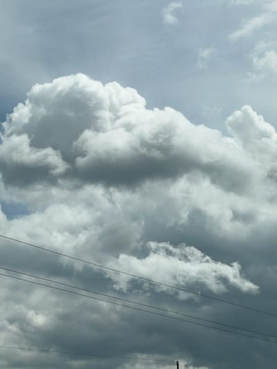 This is a photograph taken outdoors on a cloudy day, likely in Hrabovets, Ukraine. The frame is dominated by a dramatic sky filled with voluminous, grey and white cumulus clouds, suggesting impending or ongoing precipitation. Multiple dark, thin lines, consistent with electrical wires or power lines, traverse the lower portion of the image horizontally. The lighting is diffused, typical of overcast conditions, casting subtle shadows on the cloud formations. No people or specific structures are visible in the scene, which focuses entirely on the atmospheric conditions and the utility infrastructure.
