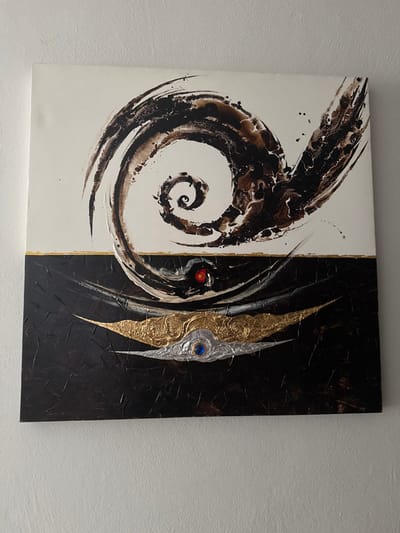 A square canvas split vertically. The left side is white with a large, dark brown spiral design. The right side is black with textured patterns and two vertically aligned decorative elements. One element is primarily gold, and the other silver, both with intricate designs and sharp pointed ends. A blue gem is set on the silver element. A small red dot is visible near the center division line, between the spiral and decorative elements. A thin gold line separates the white and black sections.