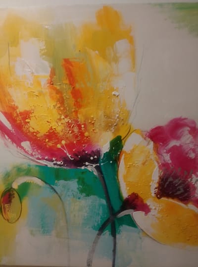 This is a photograph of an abstract painting, likely acrylic on canvas. The painting features bold, energetic brushstrokes in vibrant colors. The dominant colors are yellow, orange, pink, and teal green, with accents of white and dark purple. The subject appears to be an abstract representation of flowers, possibly poppies, given the petal shapes and colors. There are two prominent floral forms, with a larger one on the left and a smaller one on the right. The textures of the paint are varied, with some areas appearing thick and impasto, creating a tactile surface, while others are smoother. Delicate lines, possibly charcoal or a fine brush, are also visible, adding depth and definition. The overall mood of the painting is lively and expressive, with a sense of movement and organic growth. The background is a neutral off-white, allowing the colorful subjects to stand out. No text is visible in the image. The photograph itself appears to be taken indoors, likely in a home or gallery setting, with natural light illuminating the artwork. The location context of Wedel, Germany, does not provide specific visual cues within the artwork itself.