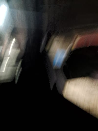 The image is a blurry, abstract photograph taken at night, likely from a moving vehicle or with a shaky camera. There are streaks of light and indistinct shapes. The overall impression is one of motion and low light conditions. Without any discernible landmarks or specific context, it is impossible to determine the location within Cumana, Venezuela.