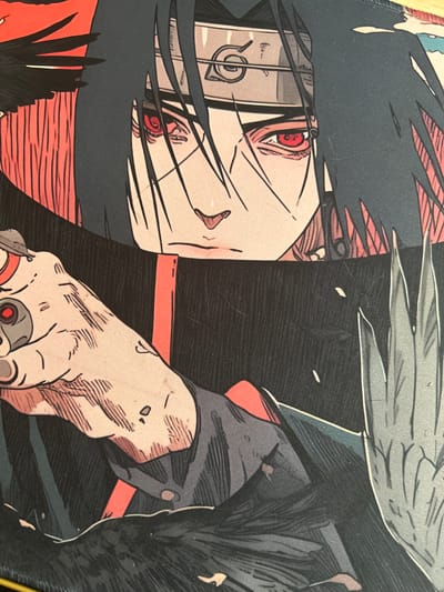 This is a close-up, detailed image of an illustration of the anime character Itachi Uchiha from Naruto. He is depicted with his signature Sharingan eyes, which are bright red. His dark hair frames his face, and he wears a Konoha headband. His left hand is visible, wearing fingerless gloves and adorned with rings. He is dressed in dark clothing with red accents. The artwork exhibits a striking, angular style with bold lines and shading. The background is a mix of dark tones and some red elements, suggesting a dramatic or intense scene. The image quality is high, allowing for a clear view of the fine details of the illustration. The location in Środa Wielkopolska, Poland is not depicted or suggested by the image itself.