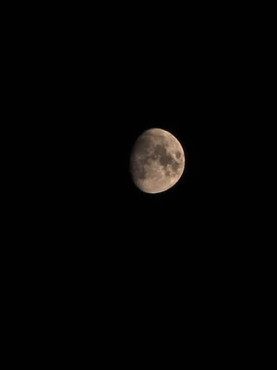 The image displays a close-up, dark, and slightly grainy photograph of the moon against a black background. The moon is partially illuminated, showing visible craters and surface features. The lower left portion of the moon is dark, indicating a crescent phase or shadowing. There are no discernible human figures, buildings, or environmental elements that would suggest a specific location, including the city of Montrouge, France.
