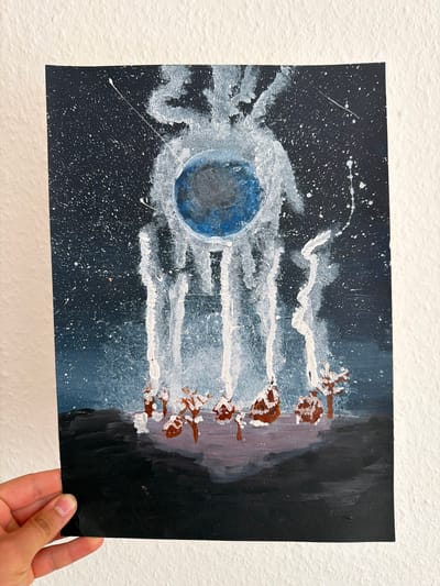 This is a close-up, top-down shot of a dark, textured wall. A rectangular piece of art, likely a painting on paper or thin canvas, is held up against it. The artwork depicts an abstract, cosmic scene. The left side of the painting features a dark background speckled with white dots, representing stars. A central blue sphere, possibly a planet or moon, is surrounded by white, wispy, streaky brushstrokes that radiate outwards. To the right, the background transitions to darker blues and purples. A row of indistinct, brown and white shapes are arranged horizontally, appearing to be figures or objects emerging from the darker background on the right, connected to the wispy white streaks from the central sphere. The overall impression is of an abstract representation of space, perhaps a celestial event or a departure from a planet. The lighting is bright, creating shadows on the wall behind the artwork. The hand holding the artwork is partially visible at the bottom right corner.
