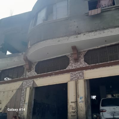 The image shows a partially destroyed building in Nuseirat, Palestinian Territories. The building features a complex façade with layered moldings, damaged walls, and barred openings. A vehicle is visible in the background, partially obscured by the building. The overall scene suggests urban decay or damage from conflict. The "Galaxy A14" watermark is visible in the lower right corner of the image.