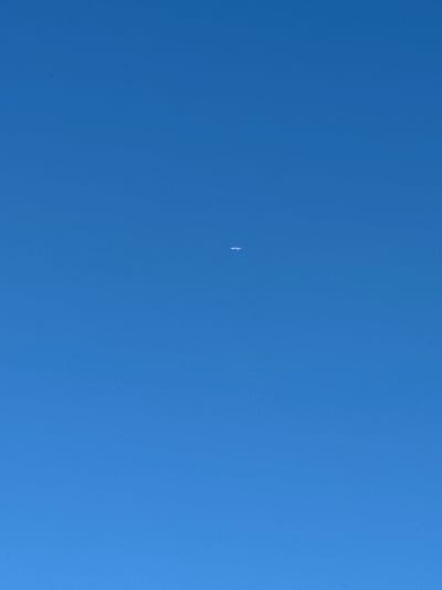 The image depicts a clear, bright blue sky. A small, white object, possibly an airplane or a contrail, is visible in the upper-middle portion of the frame. The surrounding environment appears to be an open sky, suggesting an outdoor scene likely in Yazvitsevo, Russia, given the context. No other objects, people, or discernible environmental features are present in the image.