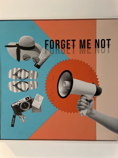 This is a collage-style artwork with a beach vacation theme, featuring several objects arranged on a background of peach and light blue geometric shapes. The text "FORGET ME NOT" is prominently displayed vertically on the left side of the image.
In the upper portion, a hand is holding a megaphone, suggesting communication or announcement. Below, scattered across the light blue section, are items commonly associated with a beach getaway: a wide-brimmed straw hat with a black ribbon, a pair of sunglasses, striped flip-flops with "ROVE" and "IN RAK" printed on them, a vintage-looking camera with keys attached, and a card that reads "ROVE AL MARIAR ISLAND," "I CAN OPEN DOORS FOR YOU," and "ROVE HOTELS." Another tag on the keys has "#EXPLORE" written on it.
The overall aesthetic is retro and summery, evoking a sense of adventure and relaxation. The color palette of peach, blue, and black and white for the photographic elements creates a vibrant yet cohesive composition. The inclusion of "ROVE" and specific location cues like "AL MARIAR ISLAND" and "IN RAK" (likely referring to Ras Al-Khaimah) grounds the artwork in a specific context within the United Arab Emirates. The mood conveyed is one of fun and reminiscence.