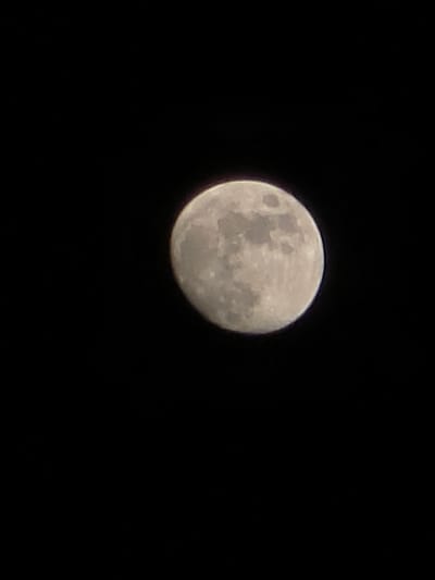 The image shows the moon against a black sky. The moon is nearly full, with a slightly shaded area on the lower right side, suggesting it's not a perfectly full moon. The moon's surface texture is visible, showing craters and maria. The location in Trachoni, Cyprus is irrelevant to the visual information presented in the image. There are no people, objects, or actions visible other than the moon itself. The environment is a night sky.