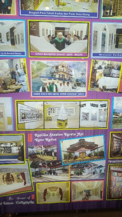 This large, vertical informational display board, located in Glantengan, Kudus, Indonesia, features a purple background and a grid of framed photographs and illustrations with yellow, green, and blue borders. It functions as an exhibit, combining biographical information, cultural heritage, religious miniatures, and historical replicas.
The top row partially shows images, including one titled "Biografi Para Tokoh Kudus dan Puisi GusJIGang." The second row features an ornate interior scene, a photo labeled "SYEKH MAHMOOD SHAHAT IQDORI MESIRI" (depicting a man in a green scarf and white cap among others near white, chest-level structures), and an image of "Miniatur Ka'bah" showcasing architectural models. The third row includes a woman in a light blue hijab engaged in an activity, a prominent image labeled "HABIB SYECH BIN ABDUL ODDIR ASSEGAF |SOLO|" (five men against a multi-story building by water and mountains), and a woman in a yellow hijab interacting with objects.
A central, large panel in the fourth row, titled "Replika Stasiun Kereta Api Kuno Kudus," presents a collage. It shows a tall, white, conical object on a yellow base, alongside interior shots of exhibition rooms with display cases, wall frames, and informational panels, indicative of a museum exhibit on the ancient Kudus railway station.
The fifth row contains an image titled "Kuno Nitsense" (an indoor display of small objects), more photos related to the "Replika Stasiun Kereta Api Kuno Kudus" theme (miniature trains, platforms, architectural renderings), and an image labeled "Perpustakaan" (a bookshelf). The bottom row displays ornate interior rooms with Islamic architectural elements, framed calligraphy (one partially titled "The House of ... Islamic Calligraphy"), and elaborate white-themed rooms with arches.