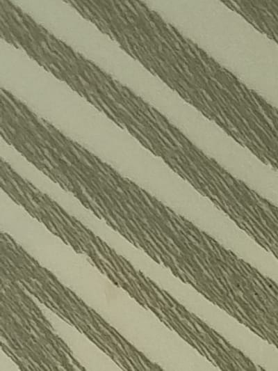 This image is a close-up of a textured surface with diagonal stripes. The stripes alternate between a pale, off-white color and a muted green color with a brushed or textured appearance. The green stripes are filled with short, parallel lines that give them a textured, almost woven look. There are a few small, dark specks visible within the green stripes, which could be imperfections in the material or part of the pattern. The image lacks any discernible subjects like people, objects, or a specific scene. It's an abstract pattern, and there are no clues about the time of day, weather, emotions, or any visible text. The provided location context of Žygaičiai, Lithuania, does not offer any visual cues within the image itself.