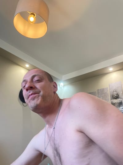 This image appears to be a selfie taken indoors, in what seems to be a living room or bedroom. The subject is a shirtless man with a shaved head and a necklace. In the background, there is a ceiling lamp, a decorative wall art featuring a Buddha statue, and recessed lighting. The location specified, Gara Elin Pelin, Bulgaria, cannot be confirmed from the visual information in the image.