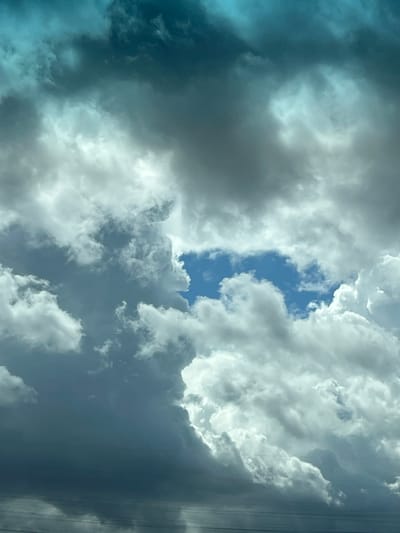 The image shows a dense, overcast sky with patches of bright blue visible through breaks in the clouds. The clouds are varied in texture and shade, with some appearing dark and stormy, while others are bright and puffy. The overall impression is of a dramatic and dynamic sky. There is no discernible urban environment visible, and therefore no information about the city of Забалацкі сельскі Савет, Belarus can be inferred from the image.