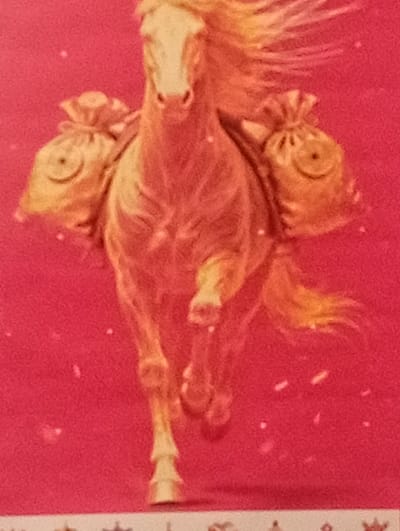 The image is a close-up, slightly blurry photograph of a horse with a light-colored mane and tail, depicted in a warm, golden hue against a vibrant pink background. The horse appears to be in motion, possibly trotting or galloping, with its front legs extended. It is carrying two large, drawstring bags, one on each side, slung over its back. These bags are also golden or tan in color and seem to be filled.
The background is a solid, bright pink with scattered small, white specks that could represent snow, glitter, or dust. The lighting in the image is warm and diffused, highlighting the golden tones of the horse and the bags.
No people are visible in the frame. The focus is solely on the horse and its cargo. The overall impression is festive or celebratory, perhaps related to a holiday or a special delivery. There is no visible text in the image. The context provided places this image in Shagonar, Russia.