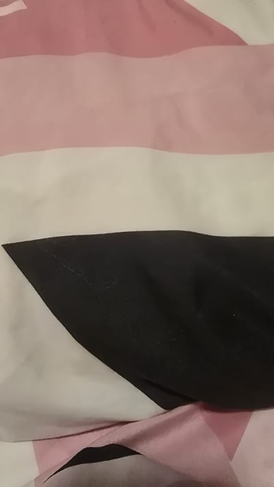 The image shows a close-up, abstract view of a fabric with horizontal stripes. The colors are pink, white, and black. The fabric appears to be layered or folded, creating shadows and highlighting the textures. There are no discernible landmarks or features that would allow for the identification of a specific location in Vlaardingen, Netherlands. The image is a still, with no actions or interactions depicted.
