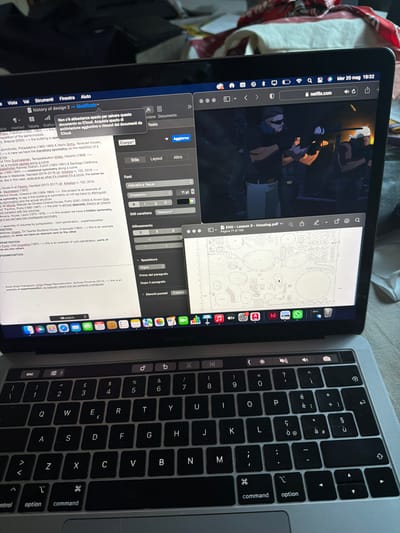 The image shows a MacBook Pro laptop open, displaying several windows. The screen on the left shows a video playing on Netflix, while the center window contains a PDF document titled "ENG - Lesson 3 - Housing.pdf", specifically page 71 of 158. The window on the right displays a text editing interface.

The laptop's keyboard is visible in the right portion of the frame, along with some of the surrounding surface.
The location in Lissone, Italy is not discernible from the content of the image.