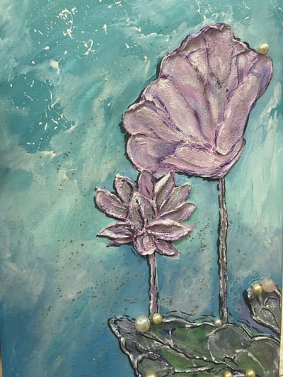 The image displays a close-up, high-angle view of a textured painting of two stylized lotus flowers against a turquoise and white abstract background. The lotus flowers are rendered in shades of purple and pink with prominent texture, appearing to have raised petals. One flower is larger and positioned higher in the frame, while a smaller one is situated below and to the left. Several pearls and light pink beads are adhered to the painting, simulating dew drops or decorative elements, particularly around the base of the flowers and on the petals of the larger lotus. The background features splatters of white paint and small reddish-brown dots, possibly representing pollen or water droplets, and subtle iridescent or glittery accents. The painting is executed on a canvas with visible texture. The scene is indoors, on a flat surface, and there is no indication of the city of Nachalovo, Russia.