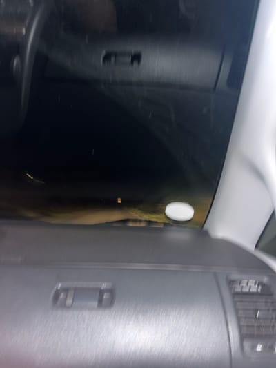 The image shows the interior of a car at night. The dashboard is visible in the foreground, with a center console and air vents. A white, circular object is on the windshield. The exterior scene through the windshield is dark and blurry, with some lights visible in the distance. Based on available data, this image was captured on June 15, 2024, at 01:28:18 local time in Novo Zhelezare, Bulgaria.