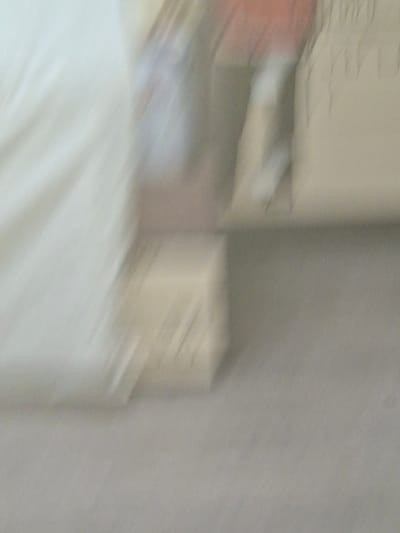 The image is a blurry, abstract depiction of an indoor scene. The subjects appear to be a collection of stacked items, possibly boxes or furniture, with some hints of color like orange and white. The background is a neutral, textured surface, likely a wall. The lighting is dim and diffused, suggesting an indoor setting without direct sunlight. The blurriness suggests movement during the capture of the image, making it difficult to discern specific details of the objects or the overall activity. No text is visible in the image. The context of Biryusinsk, Russia, does not offer any specific visual cues within the image itself.