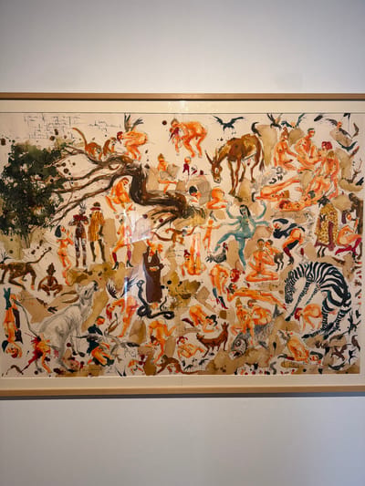 This is a framed artwork, likely a painting or drawing, featuring a chaotic and densely populated scene. The primary subjects are numerous nude and semi-nude figures in various poses, interspersed with animals such as a zebra, a horse, a fish, and monkeys. There are also depictions of what appear to be abstract forms, branches, and foliage. The style is loose and expressive, with watercolor and ink evident. The figures are rendered in warm, earthy tones, predominantly orange and brown, with some darker accents and washes.
The overall impression is one of disarray and movement, with figures seemingly falling, reaching, or interacting in an unclear narrative. Some figures are reading or holding objects, while others are intertwined or in dynamic poses. The composition is crowded, with elements overlapping and filling the entire space. There are splashes of ink and paint, adding to the sense of energy and perhaps turmoil.
Notable details include the presence of what looks like a snake, a fish with discernible scales, and the stylized black and white stripes of the zebra. The lower left portion of the artwork includes what appears to be handwritten text in cursive script, predominantly dark ink on a lighter background, which is difficult to decipher. The artwork is framed in a simple wooden frame. The background against which the artwork is displayed appears to be a light-colored wall. No specific time of day, weather, or strong emotional cues beyond a general sense of activity are immediately apparent, but the imagery could be interpreted as symbolic or allegorical. The location context of La Cuesta, Spain, provides a geographical setting but no specific visual cues within the artwork itself.