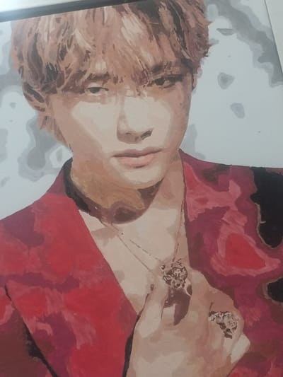 The image is a close-up painting of a young man with light brown, tousled hair. He is wearing a red jacket with a dark collar and appears to be looking slightly off-camera. He has a delicate necklace with a circular pendant and is wearing two rings on his right hand. The painting uses broad strokes and a limited color palette, with shades of red, brown, beige, and gray dominating the scene. The background is abstract and light gray, creating a soft contrast with the subject. The painting is framed by a thin black border at the top. There is no discernible information about the location in the city of Akbasheva, Russia, as this is a painting and not a photograph of a specific place.