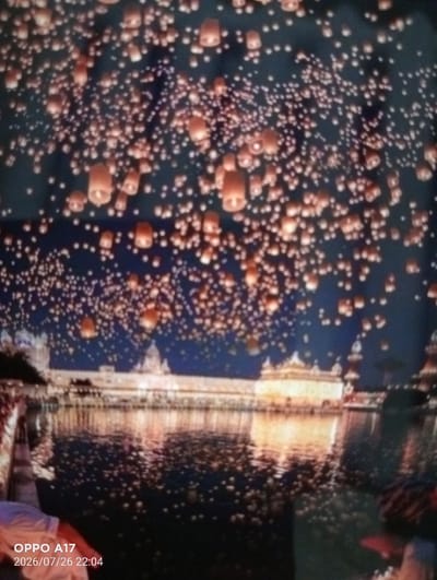 The image depicts a nighttime scene of many illuminated lanterns floating in the sky above a body of water. A large, ornate building with golden domes and intricate architecture is reflected in the water. The overall atmosphere is festive and serene. The image was taken on July 26, 2026, at 22:04, and the camera used was an OPPO A17. There are no discernible people or specific actions taking place in the image itself, other than the presence of the lanterns and the building. The location is identified as the city of Құмөзек, Kazakhstan.