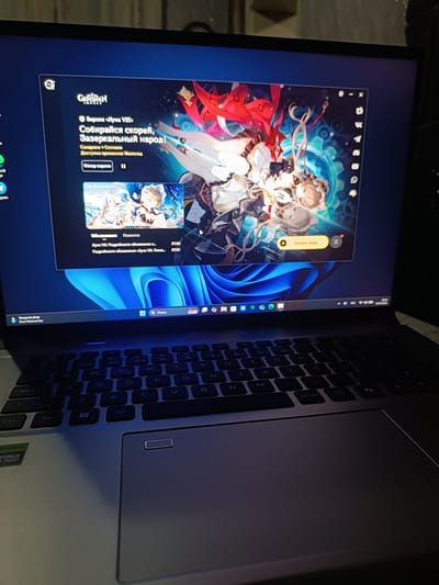 This image shows a laptop with the Genshin Impact game launcher open. The launcher displays a banner for "Version VIII" of the game, with the title "Gather quickly, Mirror people!". Below the banner are two news items related to the update, dated July 2nd and July 1st. A button labeled "Start Game" is visible on the right side of the launcher. The laptop is placed on a dark surface, possibly a table. The keyboard and touchpad are visible in the foreground. The overall lighting suggests an indoor environment, likely at night. There are no people visible in the image. The location of Medveja, Moldova is not discernable from the visual information provided in the image.
